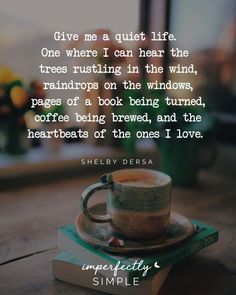 a cup of coffee sitting on top of a wooden table next to a book with the quote give me a quiet life