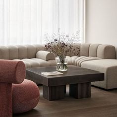 a living room filled with furniture and a vase on top of a wooden coffee table