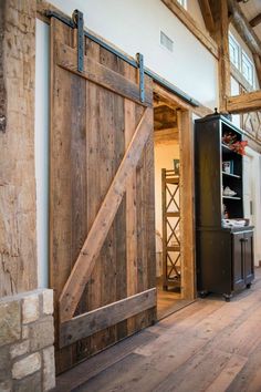 an open barn door in the middle of a room with wood floors and exposed beams