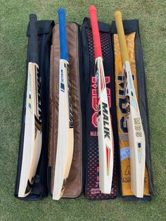 four different types of cricket bats in a case on the grass, one is empty