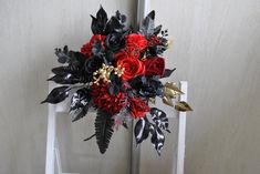 a red and black bouquet sitting on top of a white chair next to a wall