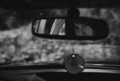 a woman's reflection in the rear view mirror of a car