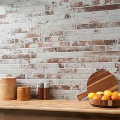 a wooden cutting board sitting on top of a counter next to oranges and jars