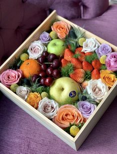 a wooden box filled with assorted fruit and flowers next to a purple couch in a living room