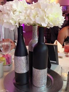 two vases with flowers in them sitting on a silver platter at a table