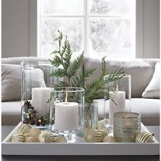 a living room with candles and christmas decorations on the coffee table in front of a window