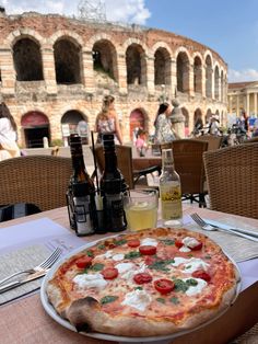 a pizza sitting on top of a pan covered in cheese and toppings next to beer bottles