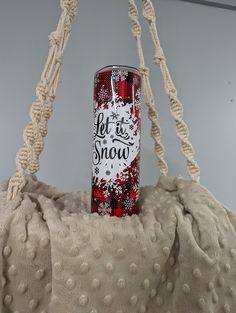 a red and white can sitting on top of a blanket next to a rope bag