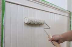 a person is painting the wall with white paint and a roller attached to it's side