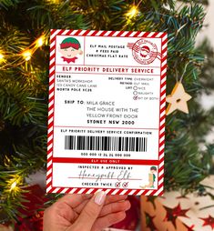 a person holding up a ticket for elf priority delivery service in front of a christmas tree