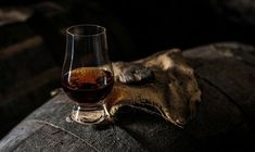 a glass of wine sitting on top of a wooden barrel next to an old cloth