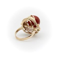 This is part of Chairish’s Fine Jewelry assortment.  At Kirsten’s Corner we love vintage coral, and this ring centers around a 12mm round sphere of well-saturated deep red Sardinian coral. The ball is centered in a tentacle-like circular mount that flows from its base and grasps the coral ball in a beautiful sci-fi fashion.  The 14k gold tentacles have a textured matte surface, ending in tiny golden balls that come together on either side of the sphere like finger tips on a hand. Circa the 1970’s, this is a great conversation piece that is both unique and elegant.   The ring is marked as 14k. It weighs 7.41 grams. The circular element measures 3/4” and the ring rises up 1/2” high on the finger. Made in Italy.   Ring size 5. Red Domed Gemstone Rings, Classic Red Coral Formal Jewelry, Formal Red Domed Rings, Formal Red Dome Ring, Vintage Red Coral Jewelry For Formal Occasions, Vintage Red Coral Jewelry For Formal Events, Elegant Carnelian Rings For Wedding, Elegant Red Dome Ring For Anniversary, Vintage Formal Red Coral Jewelry