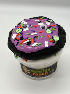 a purple frosted cookie with sprinkles on it sitting in a cup