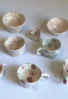 a table topped with lots of small bowls and cups filled with hearts shaped dishes on top of each other