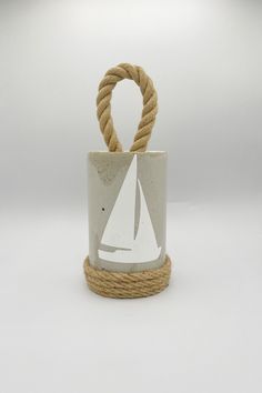 a rope wrapped around a white vase with a sailboat on it