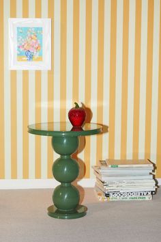 an apple sitting on top of a glass table next to stacks of books and magazines