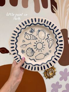 a person holding a plate with designs on it