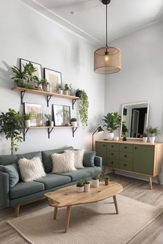 Wohnzimmer mit grüner Couch, flauschigen weißen Kissen, Holztisch, Pflanzendekoration und einer Anordnung von Wandregalen mit Rahmen und weiteren Pflanzen Room Decor Cozy, Living Room Living Room, Home Decor Ideas Living Room, Ideas Living Room, Living Room Decor Cozy, Ideas Living, Home Decor Ideas, Living Room Decor