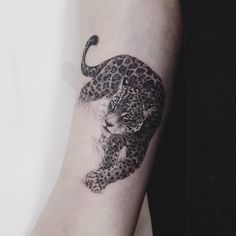 a black and white photo of a leopard tattoo on the right arm, with an animal in it's claws