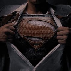 a man in a suit and tie is holding his superman shirt over his chest with the letter s on it