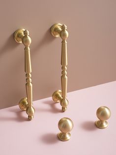 two golden door handles and three balls on a pink surface