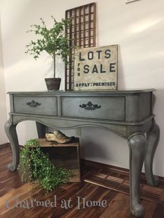 an antique desk with plants on top and a sign that says lots to sale above it