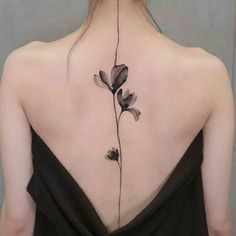 the back of a woman's neck with a flower tattoo on her left side