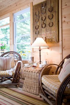 two wicker chairs and a table in a room with wood paneling on the walls