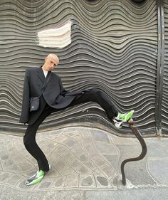 a mannequin dressed in a suit and green shoes is posed on the sidewalk