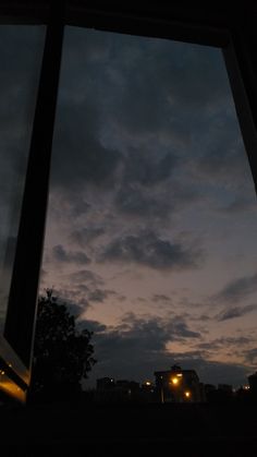 the sky is lit up at night from inside an open window, looking out onto trees and buildings