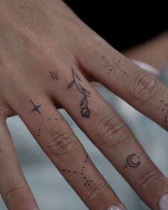 a woman's hand with three different tattoos on her left thumb and one finger