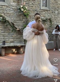 a woman in a wedding dress walking down the street with her back to the camera