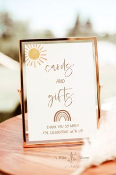 a card and gift sign sitting on top of a wooden table next to a feather