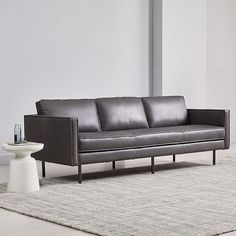 a black leather couch sitting on top of a rug next to a white coffee table