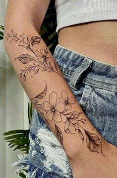 a woman's arm with flowers and leaves tattooed on the left side of her body