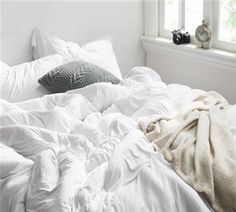 an unmade bed with white sheets and pillows