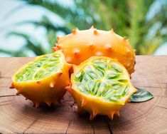 the fruit is cut in half and sitting on top of a wooden table with green leaves