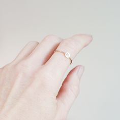 One gold letter ring. Personalize a gift she'll treasure with our gold initial ring. An adorably petite initial, imprinted on a 14k gold filled disk - paired with a super skinny (1mm) gold filled band - creates the perfect stacking ring, customized with your monogram. Lovely as a stand alone. Also sits beautifully with multiple initials stacked or our hammered gold stacking ring bands. This gold initial ring arrives custom made to order in your size hand stamped with the letter of your choice. A Dainty Rings With Initials For Everyday, Dainty Everyday Rings With Initials, Personalized Yellow Gold Initial Ring For Everyday, Minimalist Yellow Gold Stackable Rings With Initials, Everyday Personalized Yellow Gold Initial Ring, Minimalist Stackable Initial Ring For Promise, Minimalist 14k Gold Initial Ring For Promise, Minimalist Stackable Initial Promise Ring, Dainty Yellow Gold Initial Ring For Everyday