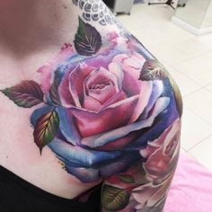 a woman's chest with a pink rose tattoo on her left arm and shoulder