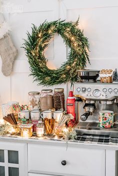 a kitchen counter topped with lots of christmas decorations and coffee maker next to a wreath