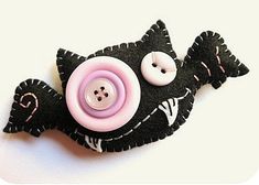 there is a black and pink button on the back of a fish brooch that has two buttons attached to it