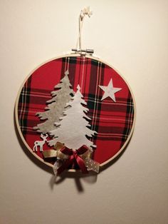 a red and black plaid christmas ornament hanging from a wall with a tree on it