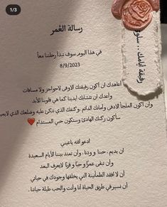 a piece of paper with arabic writing on it and a rose pinned to the side