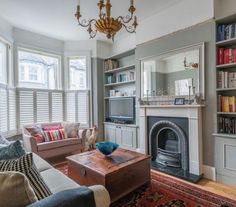 a living room filled with furniture and a fire place under a chandelier next to a window