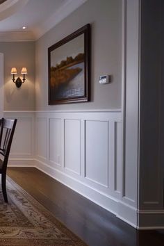 a dinning room table and chairs in front of a wall with white paneling