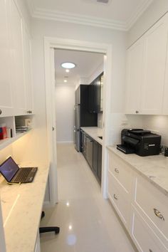 a laptop computer sitting on top of a counter in a kitchen next to white cabinets