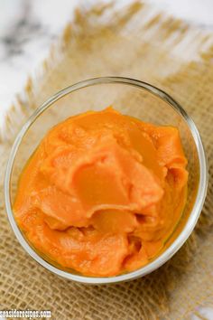 a glass bowl filled with orange colored food on top of a burlap cloth