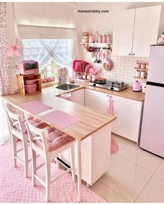 a pink and white kitchen with lots of decor on the countertop, chairs, stove top oven and refrigerator