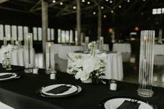 the table is set with white flowers and black napkins