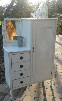 a white cabinet with drawers and a mirror